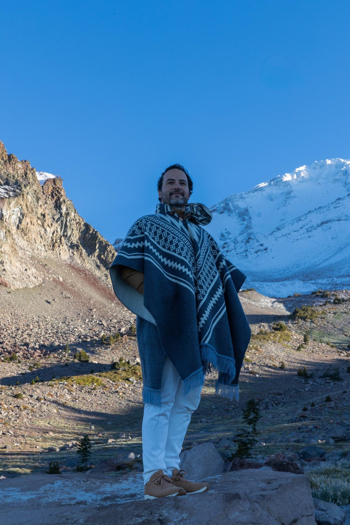 Rael Luz de poncho, diante de uma montanha nevada