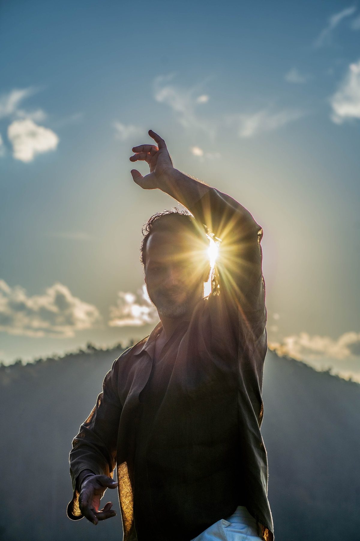 Rael Luz com o braço erguido e o sol atravessando a mão